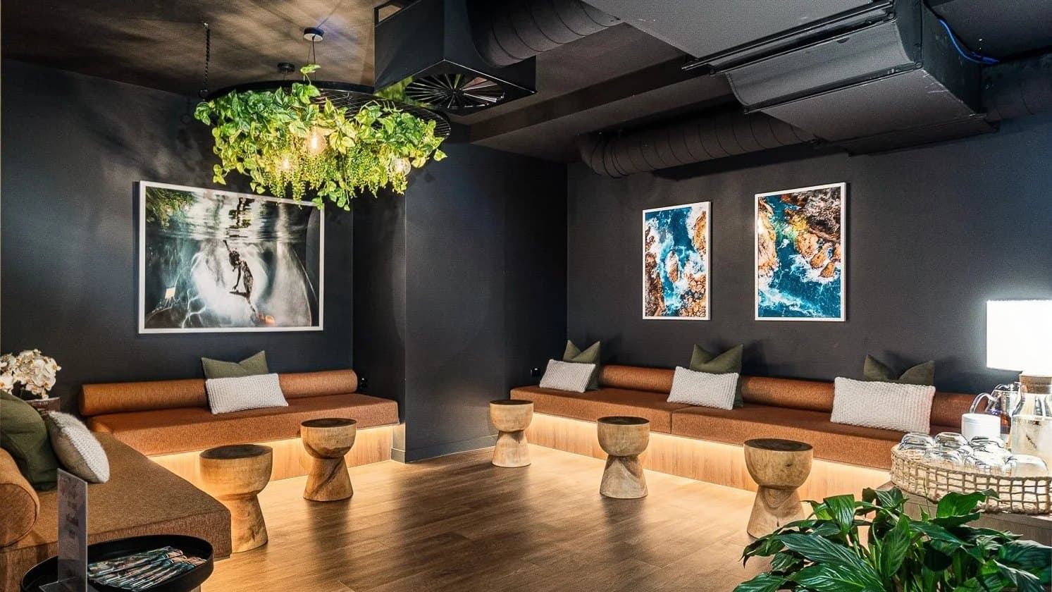 The dimly lit City Cave relaxation lounge, with banquette seating, timber stools and hanging plants